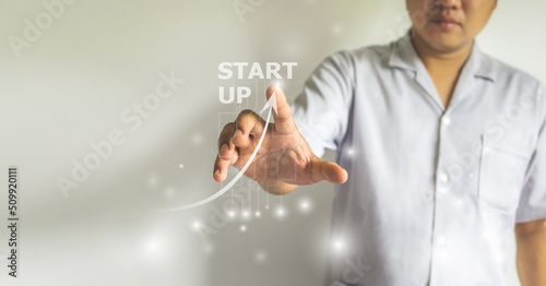 Start up business concept, business man hand point at start up letters with grow up arrow icon.
