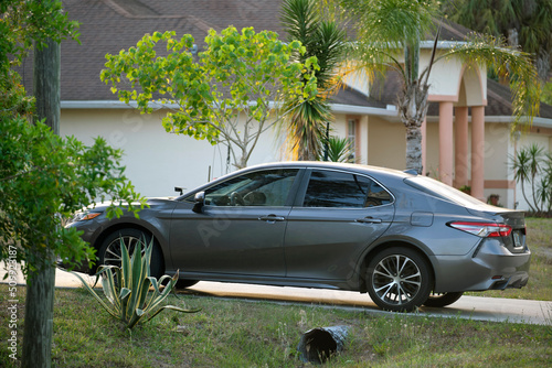 Photography Car parked in front of wide garage double door on concrete driveway of new moder