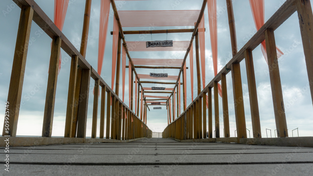 Obraz premium a beach pier, for visitors' refreshing activities, taking pictures of men, while observing the beach