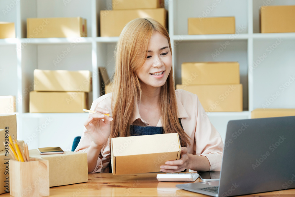 Online small business owner writing address on parcel box.