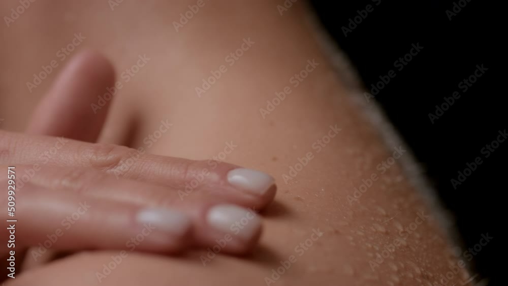 Macro shot of good-looking slim white-skinned woman strokes her wet nude shoulder turning on black background | Wet skin texture shot for clean skin concept Macro shot of good-looking slim white-skinned woman strokes her wet nude shoulder turning on black background | Wet skin texture shot for clean skin concept