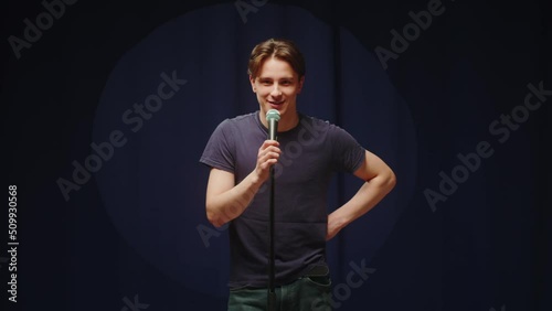 StandUp cafe, comedy concert. Man telling jokes on stage close-up. Male comedian speaking with audience using microphone, humorous monologue. Mentor coach training. photo