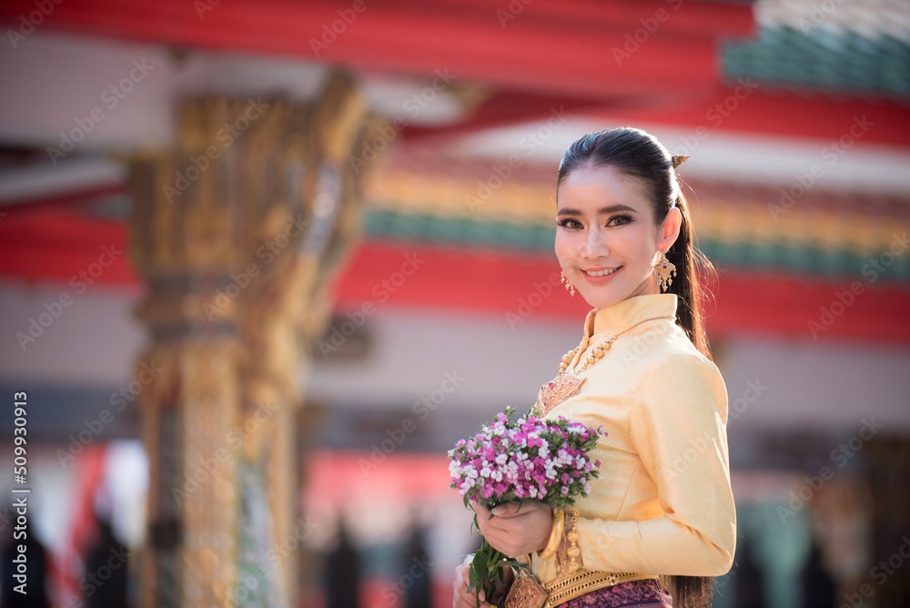 Portrait of an Asian woman in traditional Thai dress in natural light and a Thai temple