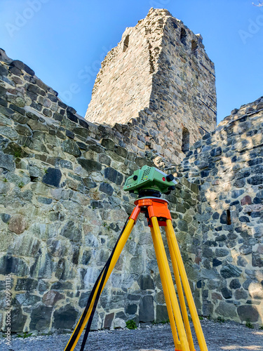 Digital level in front of church ruins