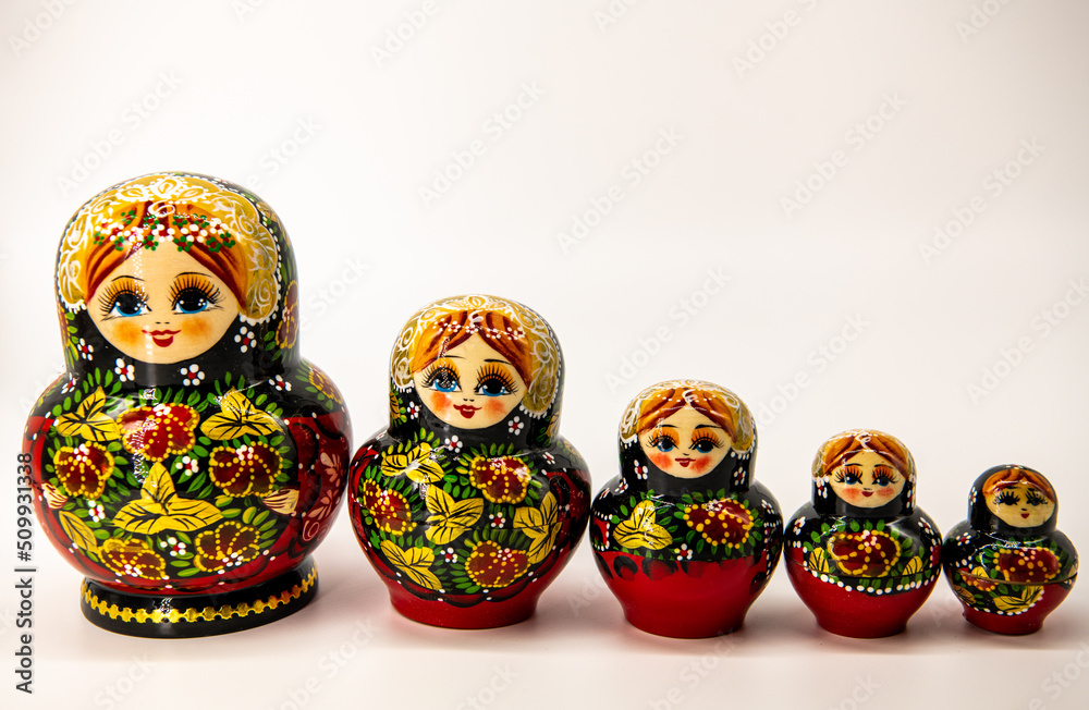 Close up on five Matrioshka Russian wooden dolls of different sizes put into one line isolated on white background, copy space for text, red, golden, green colors Close up on five Matrioshka Russian wooden dolls of different sizes put into one line isolated on white background, copy space for text, red, golden, green colors