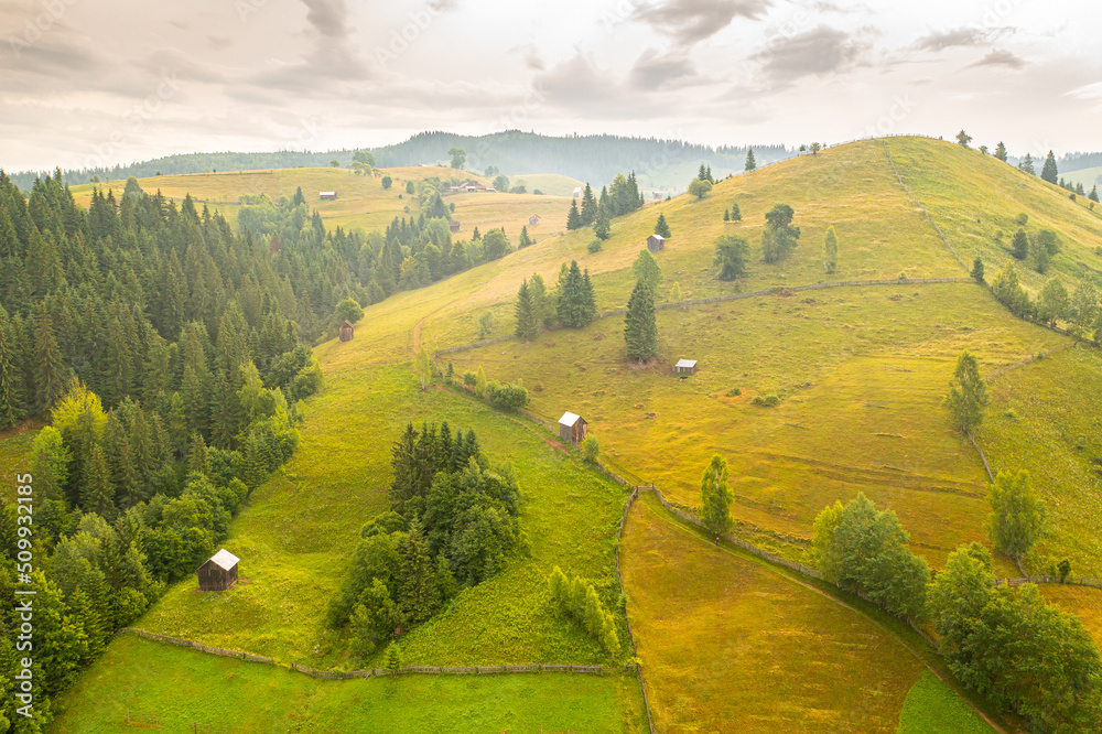 Authentic rural landscape in Romania, in Maramures and Bucovina area. Aerial view with agriculture fields, old houses and cottage on hills during a beautiful summer morning. Travel to Romania.