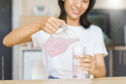 Cozy lifestyle concept, Young woman pour water from jug into glass while having snack at home