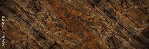 Brown rock texture with cracks. Rough mountain surface. Close-up. Stone background for design. Web banner. Wide. Panoramic. 