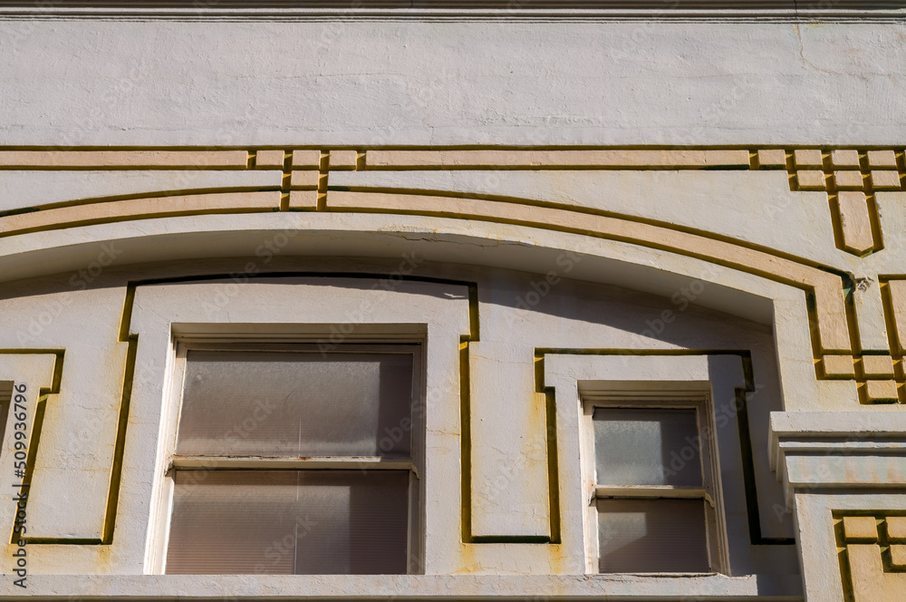 Obraz premium Faded and Decaying Arched Facade and Windows on an Art Deco Style Building.