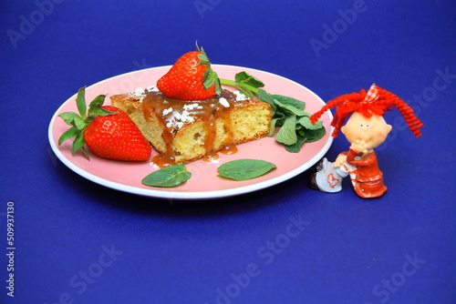 brownies with strawberries. on the plate. bay leaf, souvenir figurine of a girl. Confectionery, cakes. food. sweet concept. 