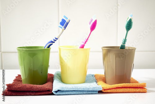 colorful toothbrushes in mugs on napkins on the bathroom table