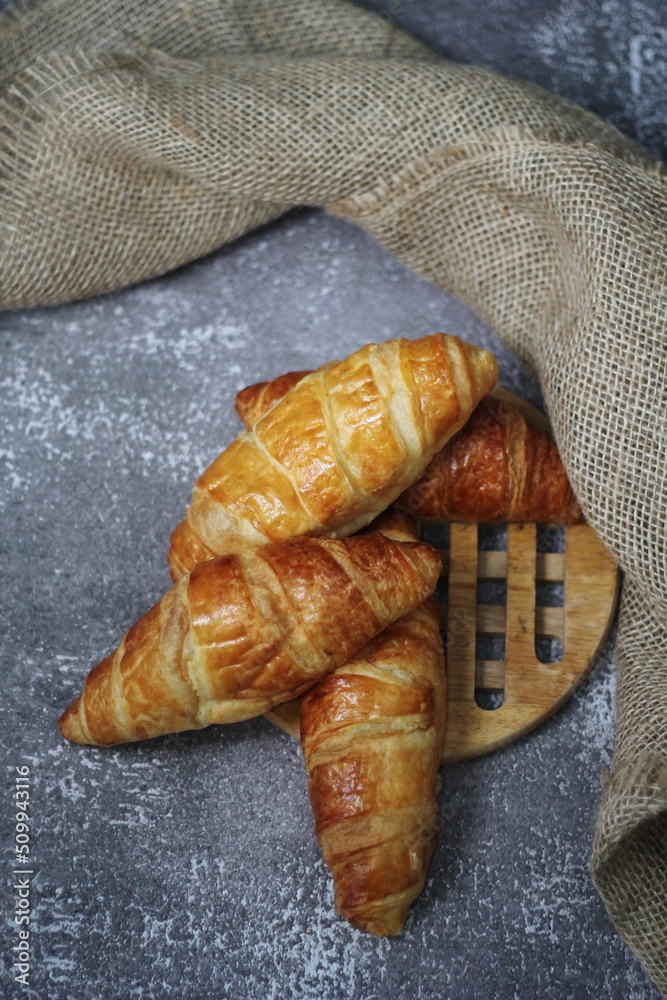 Croissant bread stacked on the table with wooden plates and sackcloth.