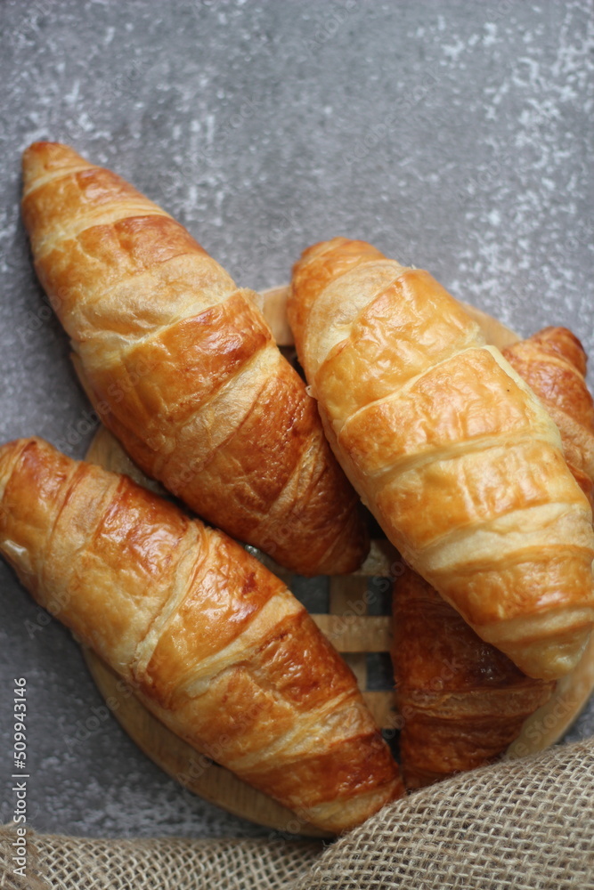 Croissant bread stacked on the table with wooden plates and sackcloth. Croissant bread stacked on the table with wooden plates and sackcloth.