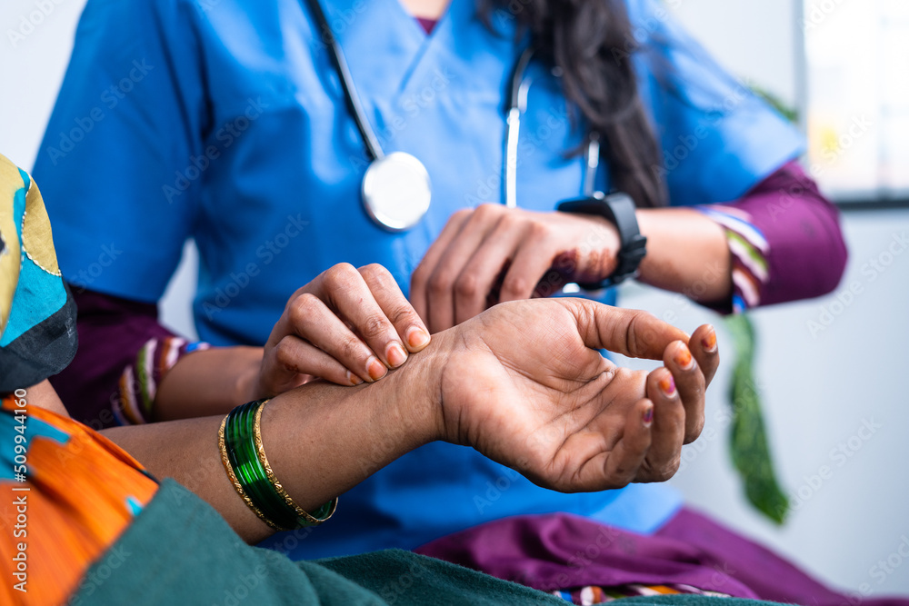 close up shot of doctor counting pulse by holding hand of sick patient - concept of health check up, medical consultation and diagnosis