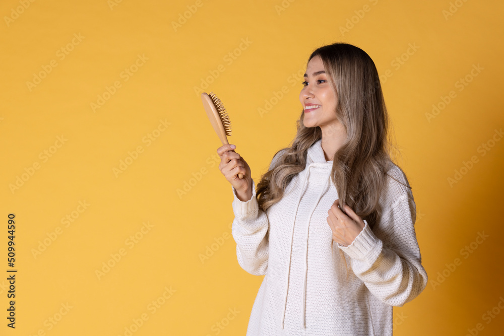 Asian woman holding a hairbrush with a happy smile Asian woman holding a hairbrush with a happy smile