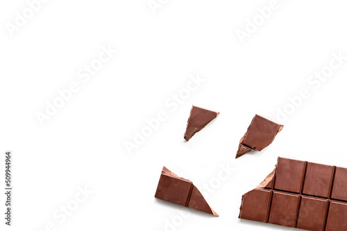 Broken organic milk chocolate bar on isolated white background from above