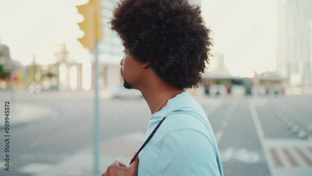 Closeup of young African American man in light blue t-shirt crossing the road at crosswalk. lifestyle concept. slow motion Closeup of young African American man in light blue t-shirt crossing the road at crosswalk. lifestyle concept. slow motion