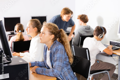 Fifteen-year-old schoolgirl, studying at school in an informatics lesson in the classroom, sitting at the computer