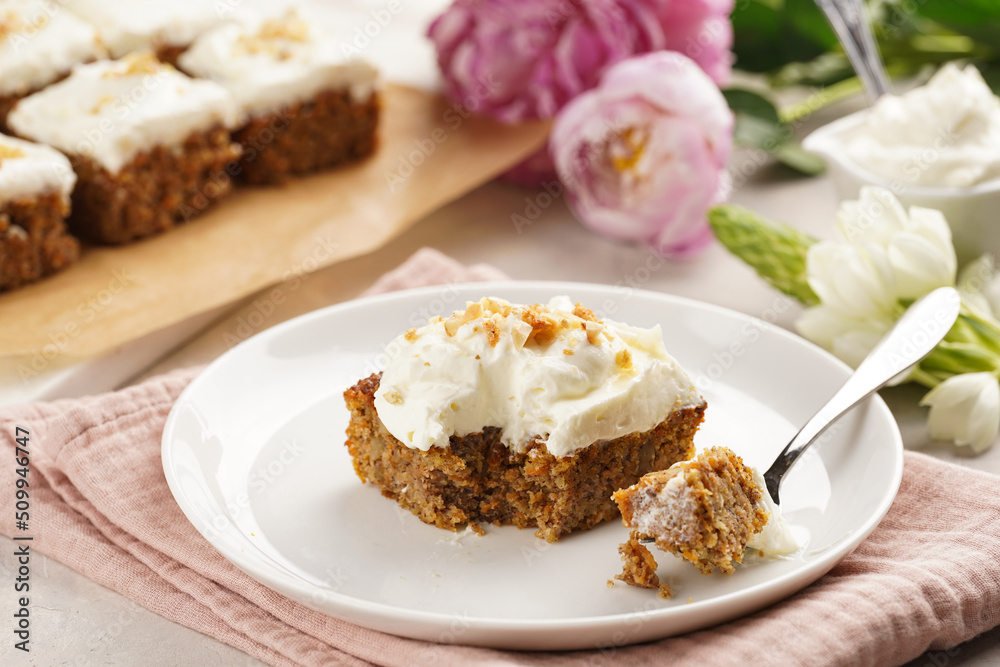 Homemade pastry carrot-walnut cake with grounded almonds and hazelnuts and white cream cheese top layer on white plate on pink napkin Homemade pastry carrot-walnut cake with grounded almonds and hazelnuts and white cream cheese top layer on white plate on pink napkin