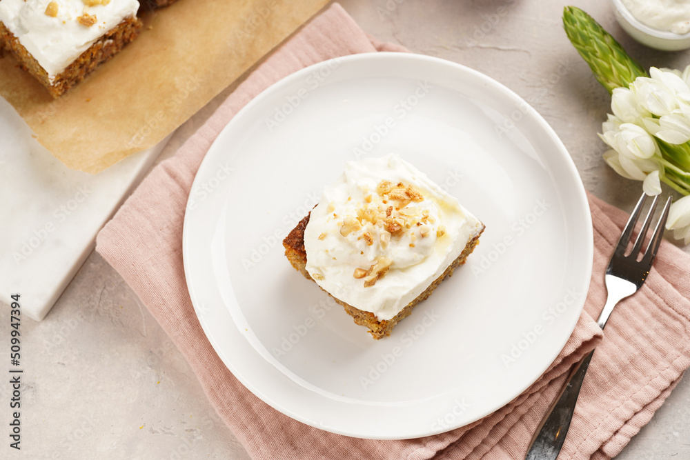 Homemade pastry carrot-walnut cake with grounded almonds and hazelnuts and white cream cheese top layer on white plate on pink napkin Homemade pastry carrot-walnut cake with grounded almonds and hazelnuts and white cream cheese top layer on white plate on pink napkin