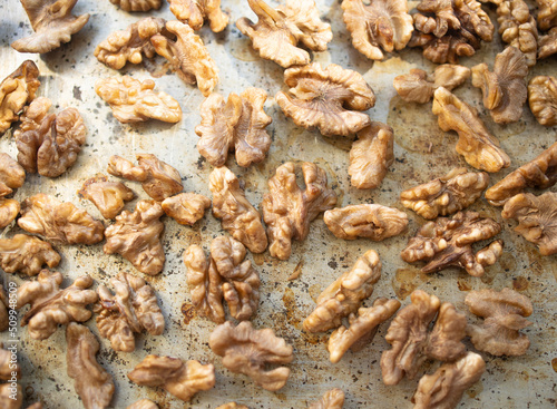 Roasted walnut lies on a metal baking sheet. Protein, healthy nuts, shortage of walnuts, more expensive snacks. © Olga