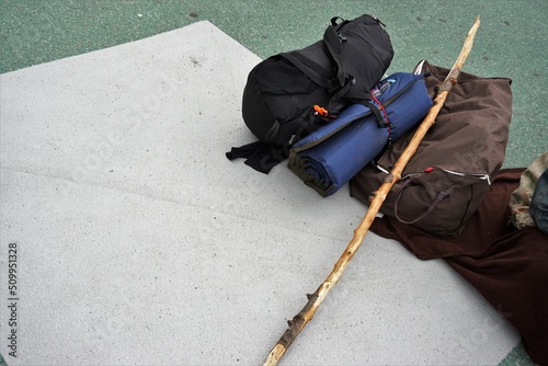 Reisegepäck mit Stock von Obdachlosem auf Straße liegend 