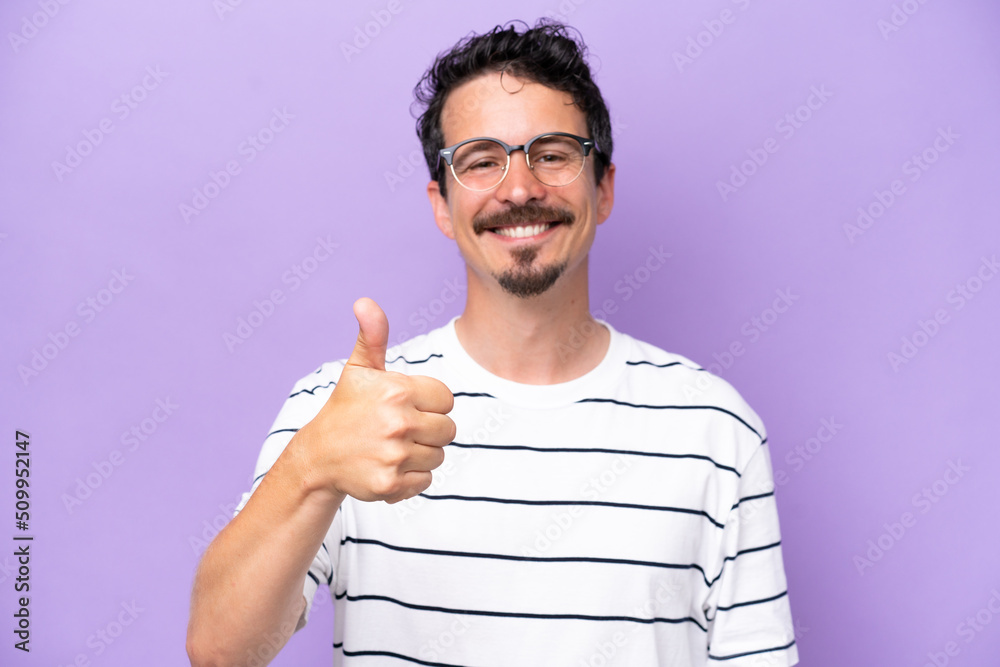 Young caucasian man isolated on purple background With glasses and with thumb up Young caucasian man isolated on purple background With glasses and with thumb up