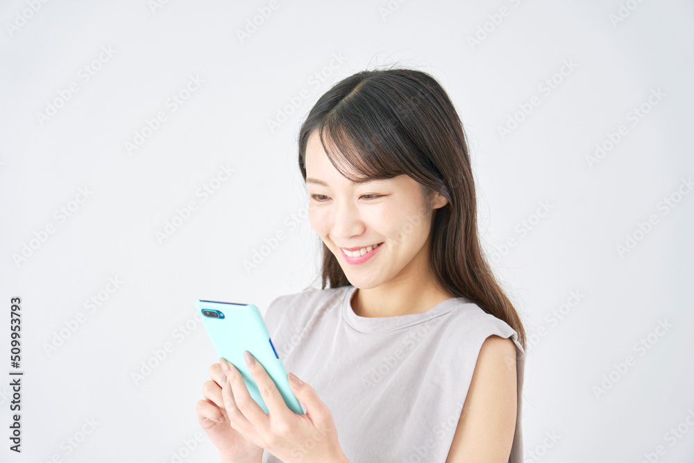 白背景でスマホを使う笑顔の女性 白背景でスマホを使う笑顔の女性