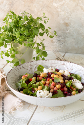 a bowl of salad with baked beets, chickpeas and pomegranate on a light table