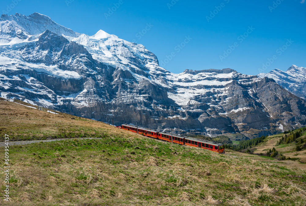  Red train to Jungfraojoch  over snowy peaks of Swiss Alps.