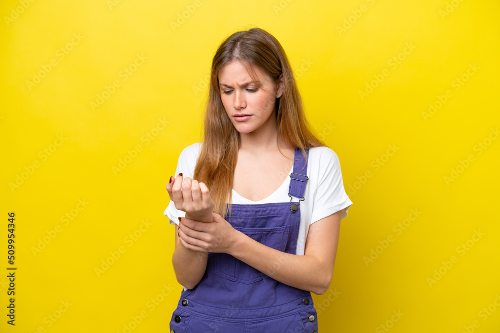 Young caucasian woman isolated on yellow background suffering from pain in hands Young caucasian woman isolated on yellow background suffering from pain in hands