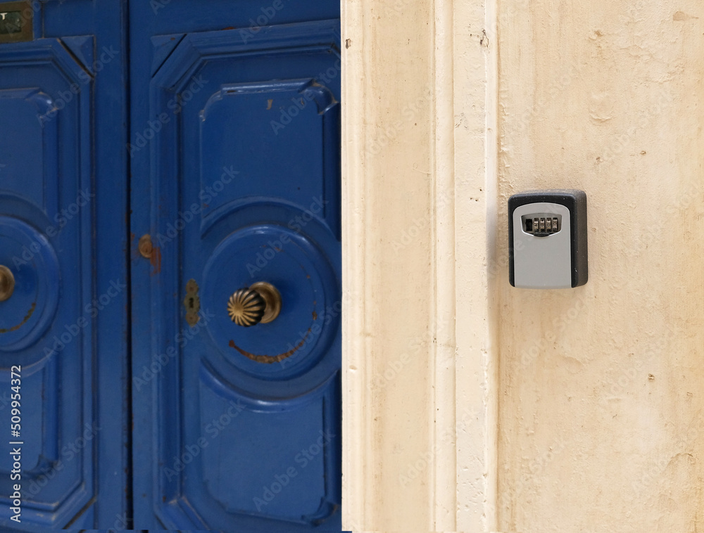 Smart key lock mounted on wall for renting apartment. Safe Key Box is used when the guest arrives at the touristic flat and the host can't open the door. Safe access to living space. Blue vintage door Smart key lock mounted on wall for renting apartment. Safe Key Box is used when the guest arrives at the touristic flat and the host can't open the door. Safe access to living space. Blue vintage door