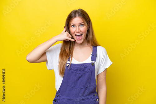 Young caucasian woman isolated on yellow background making phone gesture. Call me back sign