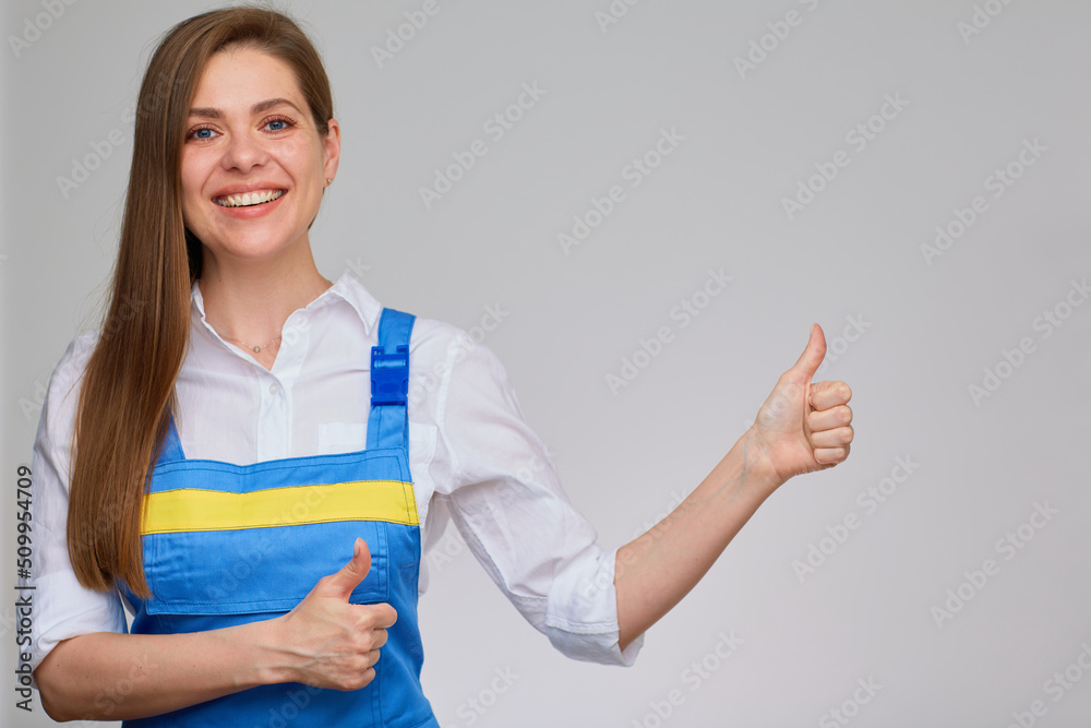 Thumb up. Smiling woman in blue overall uniform and white shirt isolated portrait. Thumb up. Smiling woman in blue overall uniform and white shirt isolated portrait.