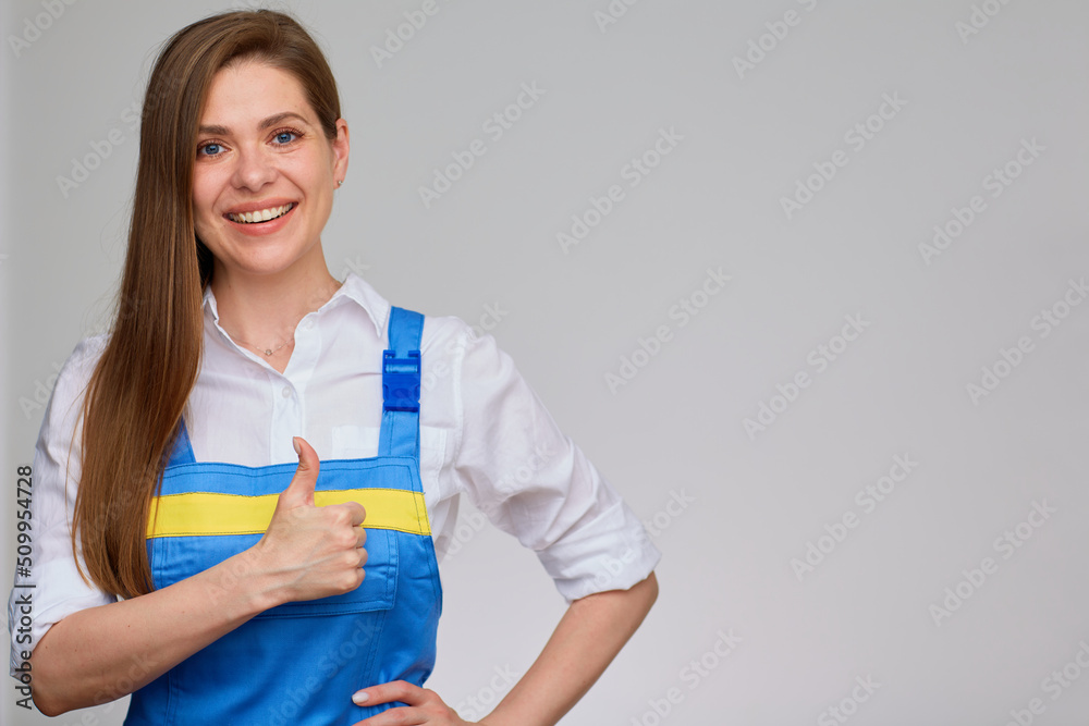 Thumb up. Smiling woman in blue overall uniform and white shirt isolated portrait. Thumb up. Smiling woman in blue overall uniform and white shirt isolated portrait.