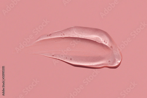 Gel texture smear stroke on pink background, skin care product snail mucin or moisturiser serum swatch photo