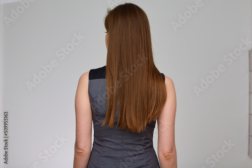 Woman with long hair stands back. Business person isolated portrait.