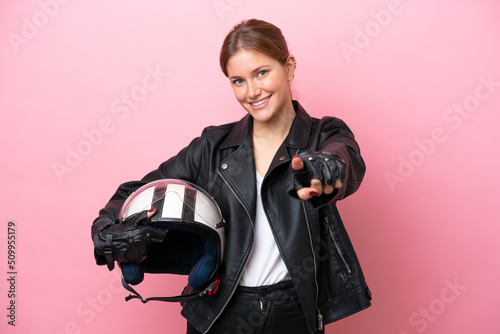 Young caucasian woman with a motorcycle helmet isolated on pink background pointing front with happy expression