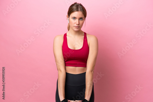 Young caucasian woman isolated on pink background stretching arm © luismolinero