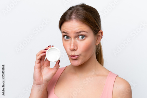 Young caucasian woman isolated on white background with moisturizer