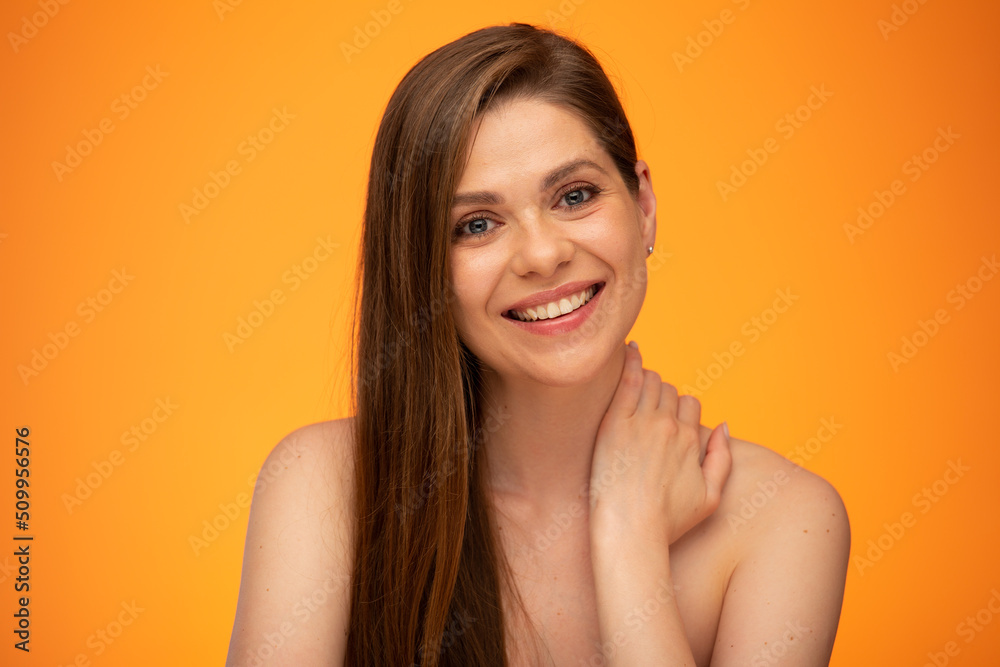 Laughing woman with long hair and bare shoulders touching her neck. isolated female close up portrait on orange background. Laughing woman with long hair and bare shoulders touching her neck. isolated female close up portrait on orange background.