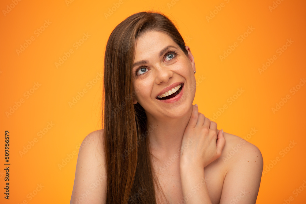 Laughing woman with long hair and bare shoulders touching her neck and looking up. isolated female close up portrait on orange background. Laughing woman with long hair and bare shoulders touching her neck and looking up. isolated female close up portrait on orange background.