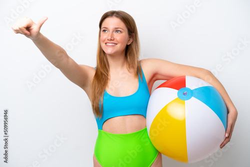 Young woman holding beach ball in holidays isolated on white background giving a thumbs up gesture