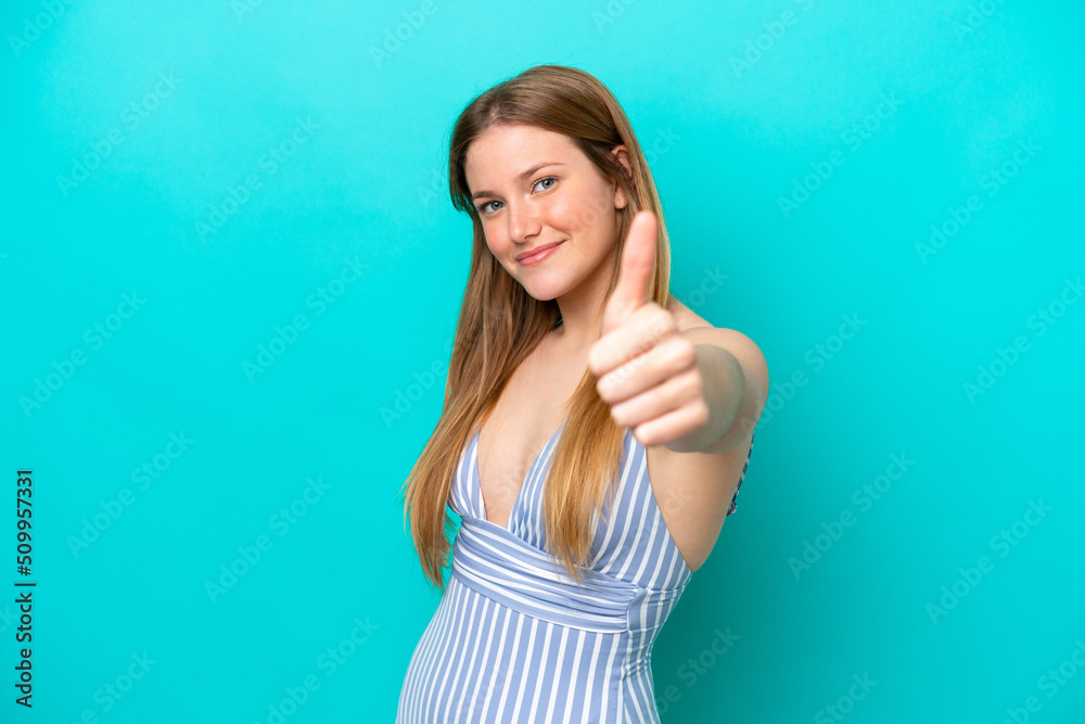 Young woman isolated on blue background in swimsuit in summer holidays and with thumb up Young woman isolated on blue background in swimsuit in summer holidays and with thumb up