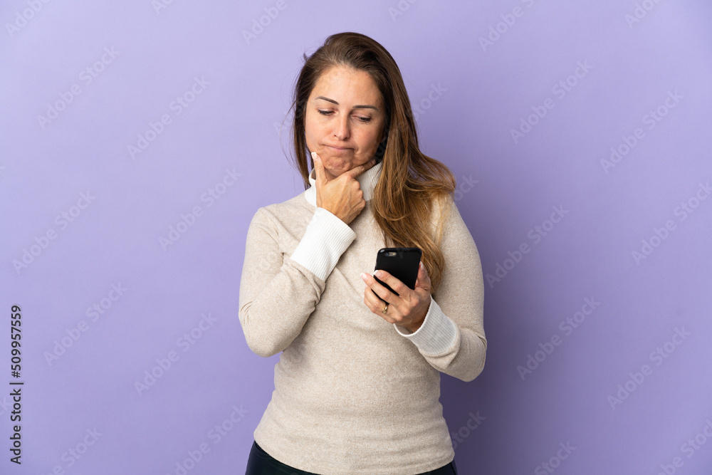 Middle age Brazilian woman isolated on purple background thinking and sending a message