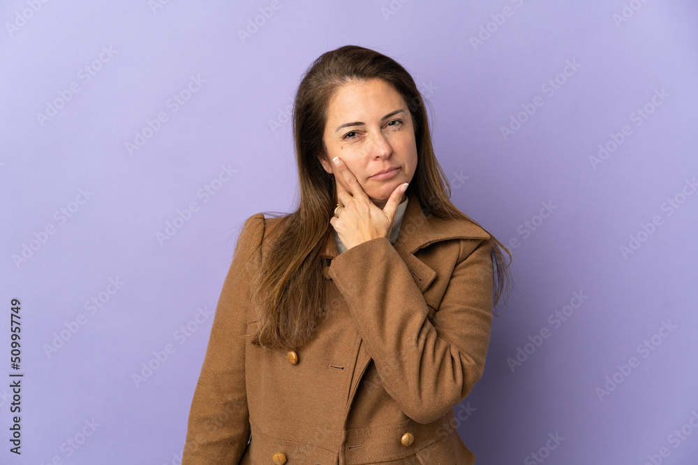 Middle age Brazilian woman isolated on purple background having doubts Middle age Brazilian woman isolated on purple background having doubts