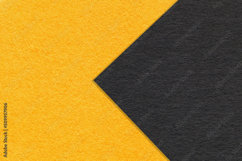 Texture of black and yellow paper background, half two colors with arrow, macro. Structure of orange craft cardboard. Texture of black and yellow paper background, half two colors with arrow, macro. Structure of orange craft cardboard.
