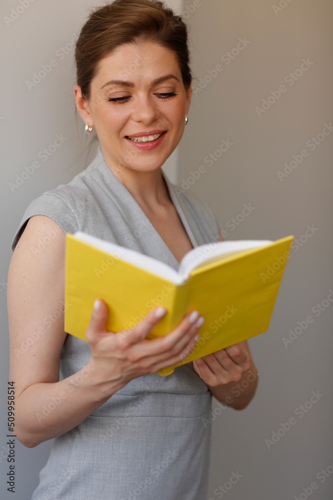 Smiling woman looking in open book. Woman teacher in dress. Smiling woman looking in open book. Woman teacher in dress.