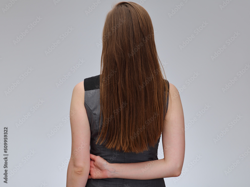 Woman with long hair in gray dress standing back. isolated female portrait.