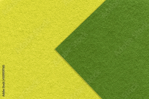 Texture of green and yellow paper background, half two colors with arrow, macro. Structure of olive craft cardboard.